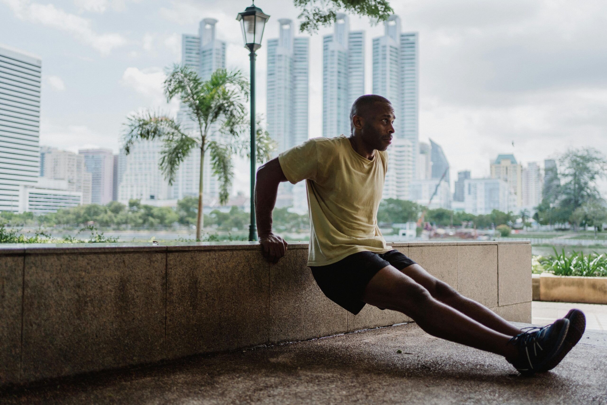 A man is doing dips with an exotic city in the background